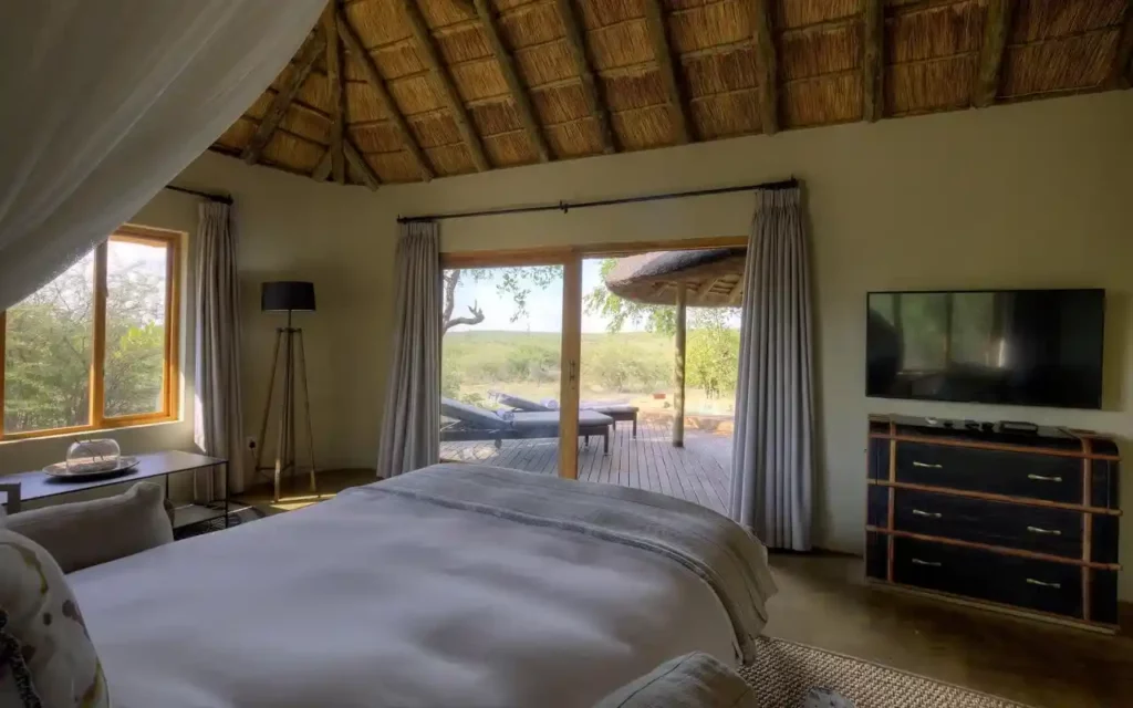 Private deck and bush view from the bedroom with double bed, TV and rustic furnishings.
