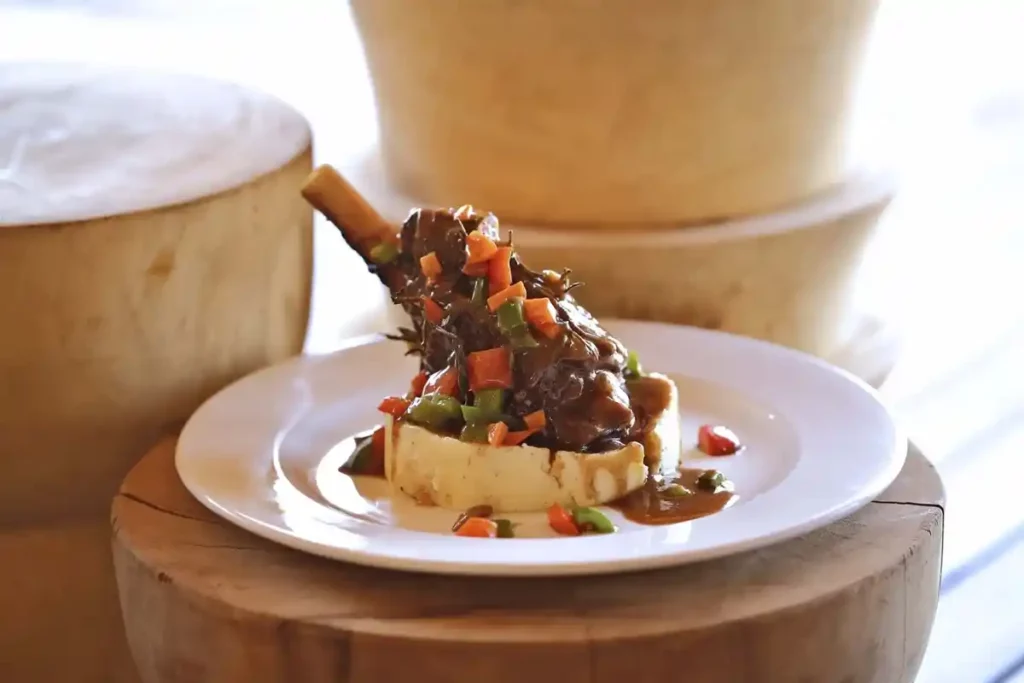 Stylish image of a plated gourmet lamb shank dinner.