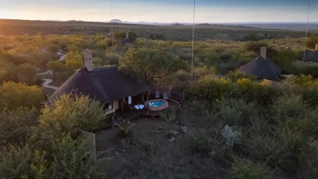 Aerial view of thatched suites with private decks and plunge pools in bushveld setting.