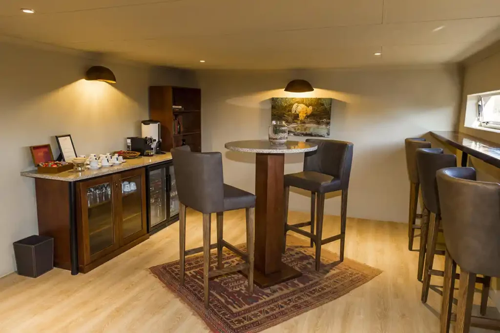 Interior of luxury hide with bar stools, bar table, coffee station and bar fridge.