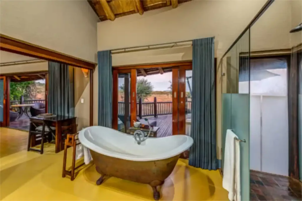Luxurious en-suite bathroom with free-standing bath with bushveld view, and a shower.