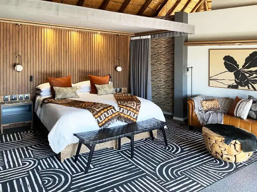 Thatched bedroom suite with King-size bed, patterned rug, seating area and rustic decor.