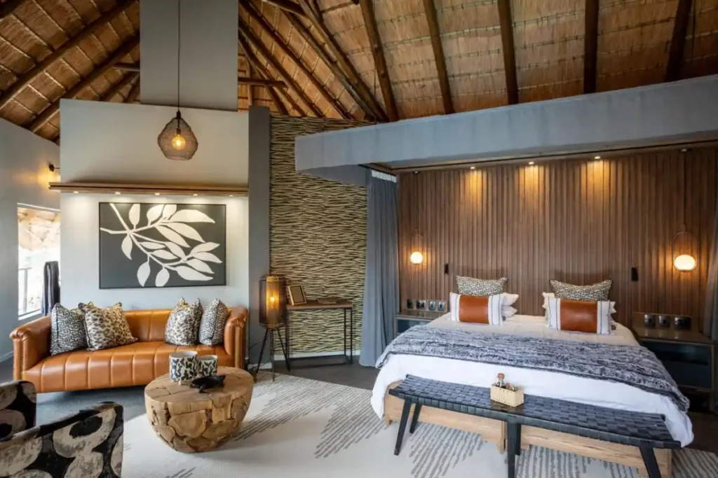 Thatched bedroom suite with King-size bed, seating area, and rustic furnishings with Afrocentric decor.