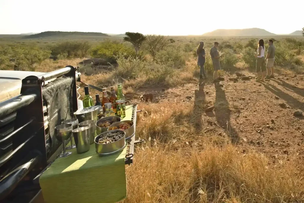 Guests admire the bushveld view while having sundowners on evening game drive.