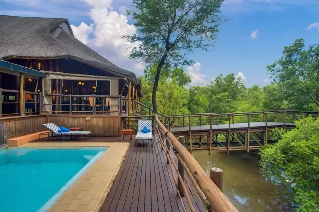 Lodge pool and deck with loungers with wooden walkway over the river.