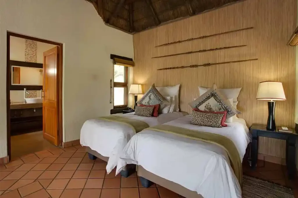 Layout of bedroom with twin beds, rustic decor and entrance to the en-suite bathroom.