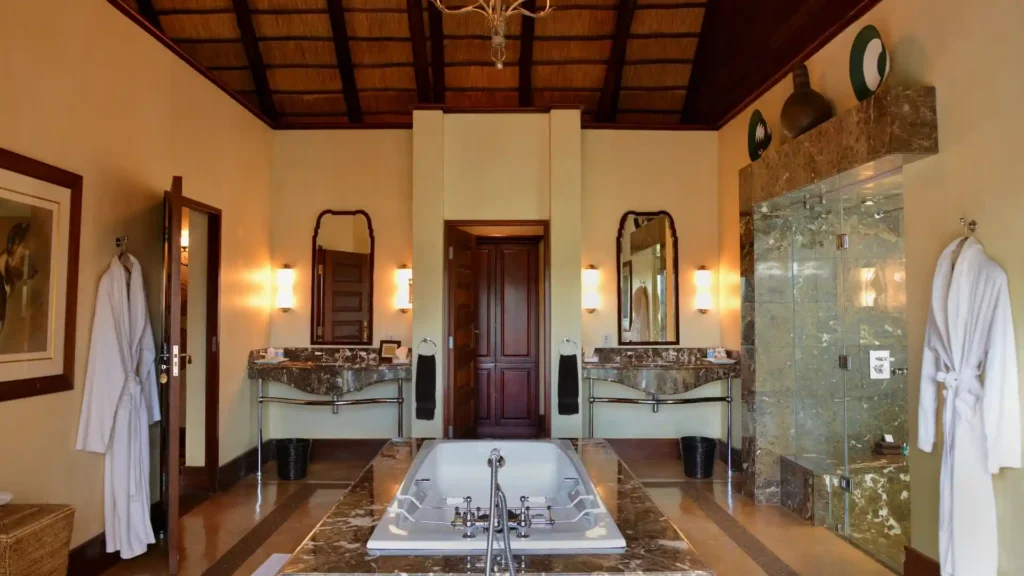 Luxury safari lodge bathroom with marble bath and thatched ceiling