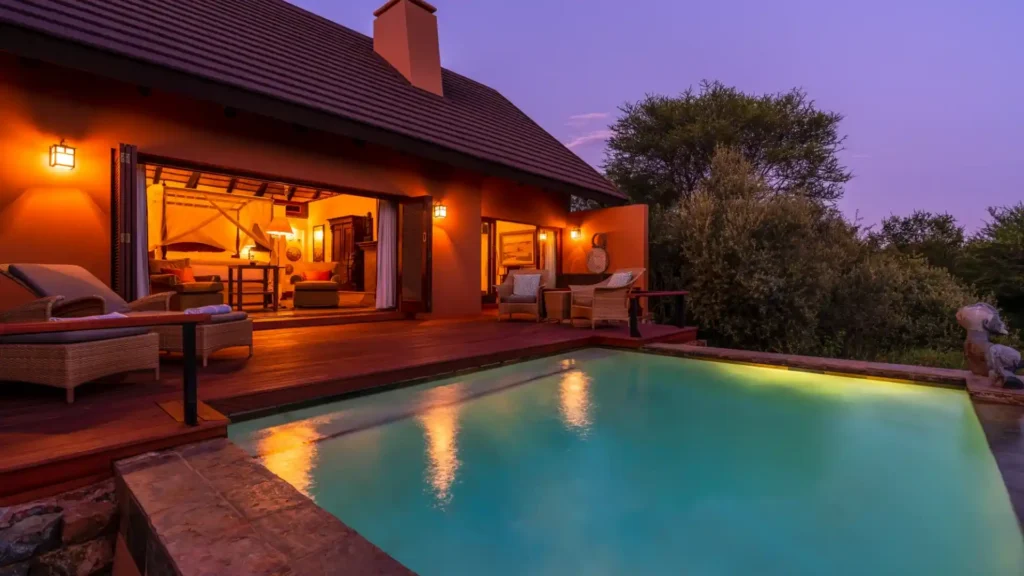 Luxury safari lodge with illuminated pool at dusk